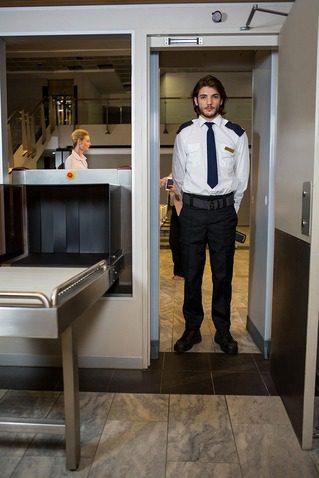 Essential security guard standing scanning door 1